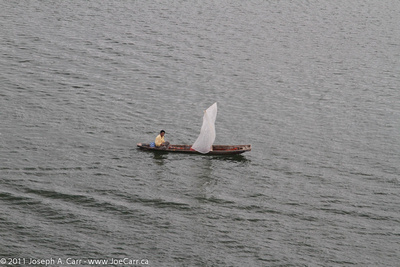 Man in dugout canoe with plastic sail on Guayas River