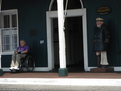 A wooden captain and a sleeping man (in his wheelchair) at the entrance to the Pioneer Inn