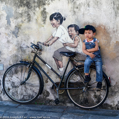 A boy sitting on street art - Kids on bicycle by Earnest Zacharevic