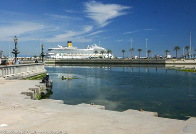 Cruise ship in Tripoli Harbour. Old man sitting by lagoon.