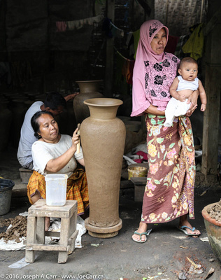 Woman making a tall pot with a younger woman holding a baby