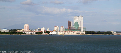 Malacca Straits Mosque built on stilts in the water and modern buildings on the shore