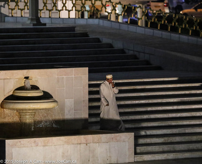 An Omani man on the steps of the Al-Zawawi Mosque at night