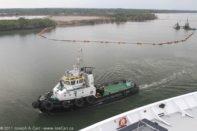 Tugboat beside Rotterdam and dredge in navigation channel of Guayas River