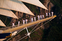 Crew standing on the bow sprit of the Royal Clipper under sail as she departs Soufriere at sunset