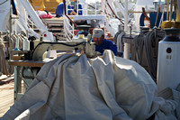 Crewman mending the sails with a sewing machine