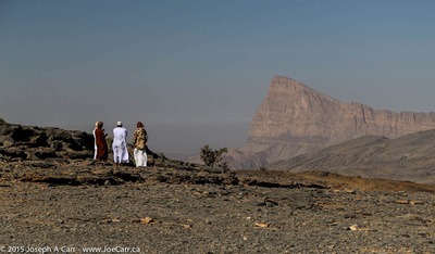 Our drivers huddled against the cold wind with Jebel Misht in the distance