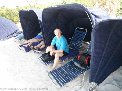 Joe in a lounge chair under a clamshell on the beach