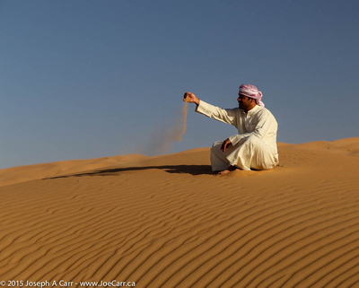 Arab man sitting on a sand dune