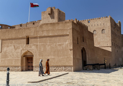 Two Arab men walk by the castle