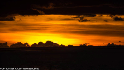 Sunset south of Bora Bora with huge storm clouds along the horizon