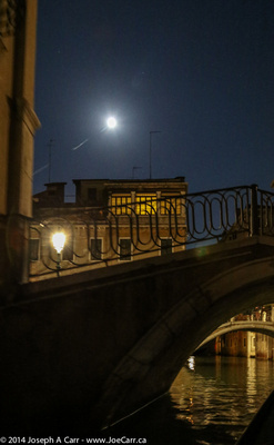 A bridge over a canal with the Full Moon behind