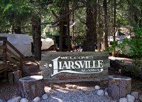 Liarsville welcome sign with camp behind