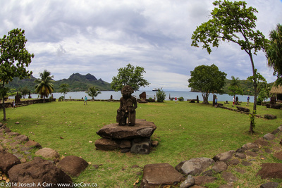 Stone statue in a park with the Statendam anchored in the harbour