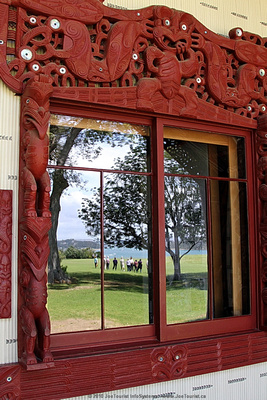 Window of Te Whare Runanga Meeting House reflecting front lawn