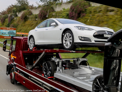 White Tesla Model S and spare chassis on a transport truck