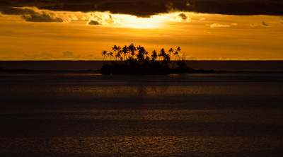 Sunset south of Bora Bora with palm trees on a motu